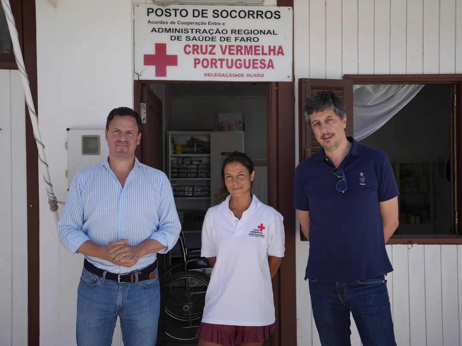 Três voluntários da Cruz Vermelha Portuguesa à entrada do posto de socorro