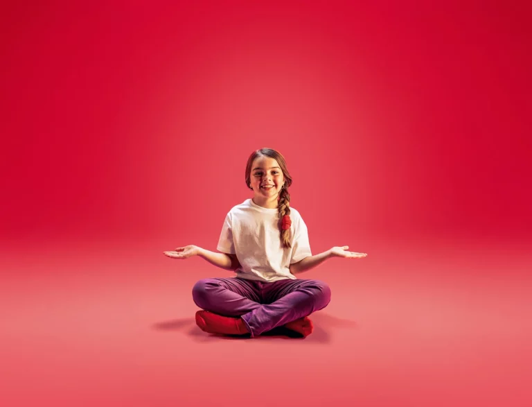 Criança de pernas cruzadas e braços abertos, sorrindo