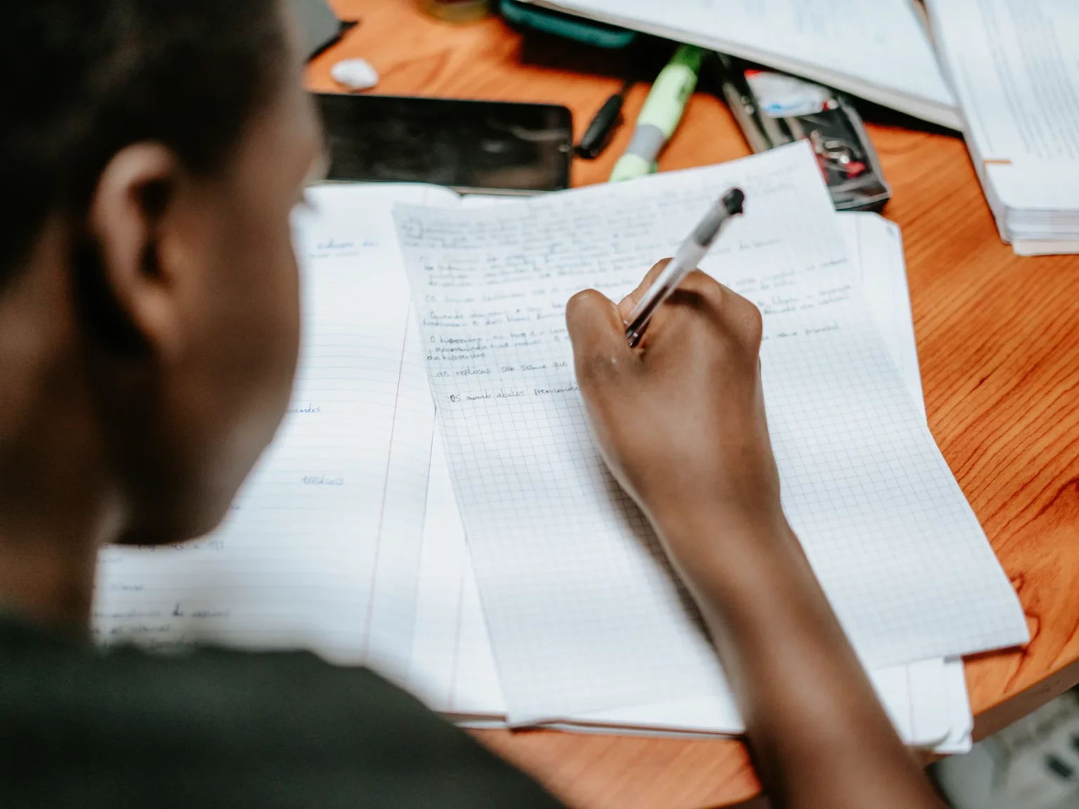 Aluno a escrever numa folha em contexto de aula