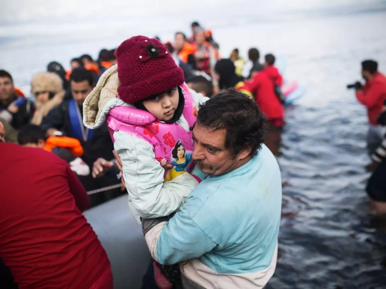 Homem com criança ao colo ao lado de uma embarcação
