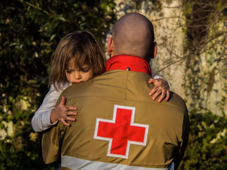 Voluntário da Cruz Vermelha Portuguesa a prestar apoio a criança